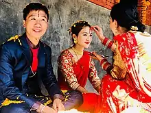 A sister applying tika to her brother and sister–in–law.