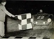 The race director Renzo Castagneto flies the chess flag to the winner Phil Hill on Ferrari.