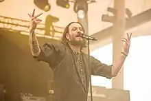 Kobi Farhi upclose, standing onstage, singing into a microphone