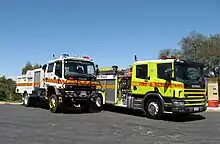 An ACT Rural Fire Service CAFS Isuzu tanker (white) and an ACT Fire Brigade Scania P94D 260 truck (yellow) pumper.