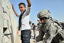 Image 8U.S. Army soldier searches an Iraqi boy, March 2011. (from History of Iraq)