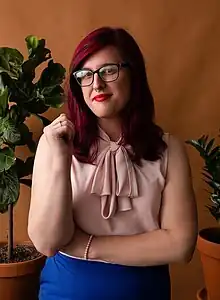 transgender woman wearing a pink blouse and blue pants