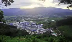 cluster of buildings surrounded by green fields and hills