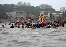 Large statue of Ganesh on the water, surrounded by people