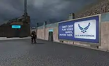 A billboard standing against a wall in a futuristic city during a rain shower. An armored man, about half its size, stands nearby looking at it. Billboard displays advertisement reading "Don't just play video games, inspire them. U.S. Air Force"