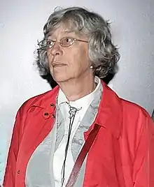 A woman wearing a red jacket, cropped from a group photograph