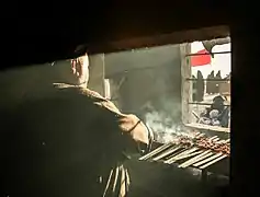 A man grilling meat for pilgrims along the path of the Arba'een Pilgrimage