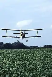 Biplane, cropduster over US field