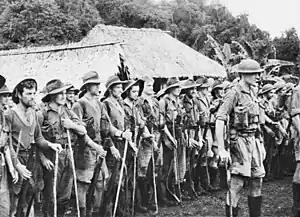 A parade of tired-looking soldiers in a jungle setting