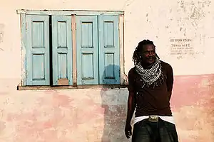 Man standing against a wall with a window to his left