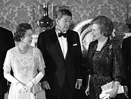 Thatcher standing with Elizabeth II and Ronald Reagan