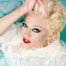 A woman laying down on a bed, wearing heavy makeup with her hand to her head, with "Madonna" written in pink capital lettters, while "Bedtime Stories" is written in sky-blue capital letters.