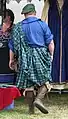 Renaissance fair attendee wearing a belted plaid. He is letting the top half hang loose at the back. While his outfit is not historically authentic, the plaid is similar.