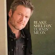 Shelton standing in front of a green background with the song's title to the right of him.