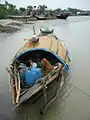 Bangladeshi fishermen resting in the shade of a sampan in Barishal