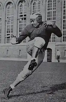 Mann in his football gear posing as if he is running