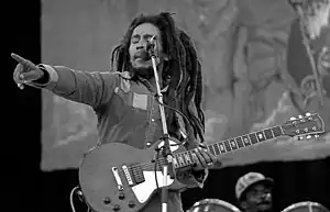 Black and white image of Bob Marley on stage with a guitar