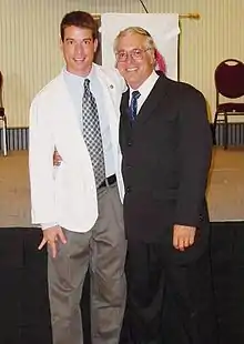 The same young man seen with his mother in the photo above, in the same setting, with an older bespectacled man on his right this time