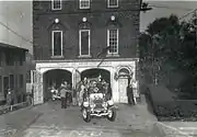 1930s fire engines leaving a brick firehouse