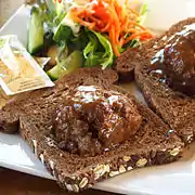 Broodje bal&nbsp;[nl], a slice of bread with a meatball and gravy, halved meatball served on slices of Dutch whole wheat bread.