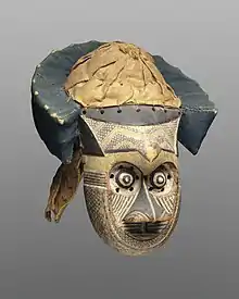 Pwoom Itok mask; late 19th century; 39.1 x 28.6 x 29.8&nbsp;cm (15.mw-parser-output .frac{white-space:nowrap}.mw-parser-output .frac .num,.mw-parser-output .frac .den{font-size:80%;line-height:0;vertical-align:super}.mw-parser-output .frac .den{vertical-align:sub}.mw-parser-output .sr-only{border:0;clip:rect(0,0,0,0);clip-path:polygon(0px 0px,0px 0px,0px 0px);height:1px;margin:-1px;overflow:hidden;padding:0;position:absolute;width:1px}3⁄8 x 11.mw-parser-output .frac{white-space:nowrap}.mw-parser-output .frac .num,.mw-parser-output .frac .den{font-size:80%;line-height:0;vertical-align:super}.mw-parser-output .frac .den{vertical-align:sub}.mw-parser-output .sr-only{border:0;clip:rect(0,0,0,0);clip-path:polygon(0px 0px,0px 0px,0px 0px);height:1px;margin:-1px;overflow:hidden;padding:0;position:absolute;width:1px}1⁄4 x 11.mw-parser-output .frac{white-space:nowrap}.mw-parser-output .frac .num,.mw-parser-output .frac .den{font-size:80%;line-height:0;vertical-align:super}.mw-parser-output .frac .den{vertical-align:sub}.mw-parser-output .sr-only{border:0;clip:rect(0,0,0,0);clip-path:polygon(0px 0px,0px 0px,0px 0px);height:1px;margin:-1px;overflow:hidden;padding:0;position:absolute;width:1px}3⁄4 in.); Brooklyn Museum (USA). This mask may have represented a wise older man at boys' initiations. One of the principal Kuba dance masks is called pwoom itok. The chief identifying characteristic is the shape of the eyes, whose centers are cones surrounded by holes through which the wearer sees