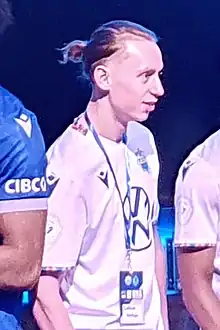 Man with pony tail standing up looking to the right