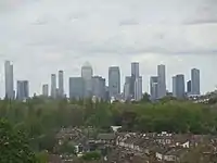The Canary Wharf and Isle of Dogs business district as viewed from Blythe Hill Fields, London Borough of Lewisham, May 2021. There are currently seven towers in this cluster that are at least 200m tall with more planned and under construction.  However, due to the proximity of London City Airport it is unlikely that any of them will exceed the height of the existing One Canada Square at 235m
