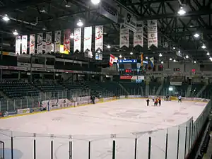Photo of ice rink with team banners hanging from the celing