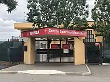 The front entrance gate of A.C. Monza's Centro Sportivo Monzello, with trees in the background