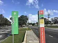 Tall bus stop pole with signage on it on the side of a road