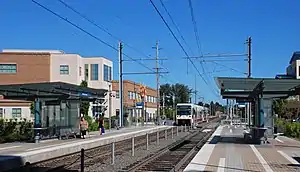 A train station with a train arriving on the left along one of two tracks