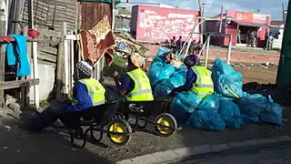 Street Cleaners in Joe Slovo Park, Dilapidated soccer field visible in the background