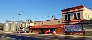 one-story brick building with sign reading McDonald's Meats, along with grain silos