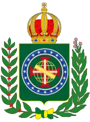 Coat of arms consisting of a shield with a green field with a golden armillary sphere superimposed on the red and white Cross of the Order of Christ, surrounded by a blue band with 20 silver stars; the bearers are two arms of a wreath, with a coffee branch on the left and a flowering tobacco branch on the right; and above the shield is an arched golden and jeweled crown.