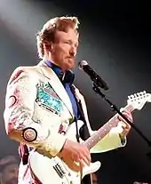 Conan O'Brien playing the guitar in a white suit