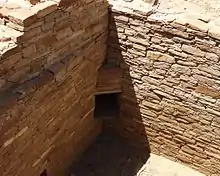 A color picture of a corner dorrway in a large sandstone wall