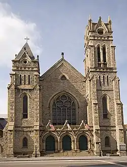 Exterior of Gothic style church built from handcut stone with a bell tower.