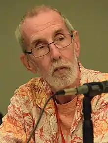 Giffen seated at a panel, wearing a Hawaiin shirt