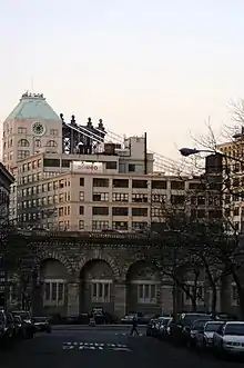 A stone viaduct approach ramp to the Brooklyn Bridge, as seen from a street in Brooklyn, with buildings to either side