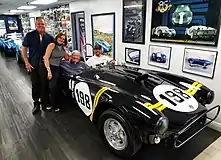 Dave MacDonald's son Rich behind the wheel of 2017 Sebring Tribute Cobra released by Shelby American and Superformance. Finished in Dave MacDonald “Cotati livery” the car is modeled after perhaps the most famous of all Shelby Cobras, CSX2128. MacDonald ran CSX2128 to its first victory at Cotati Raceway in May 1963. Also pictured is Shelby American photog Dave Friedman (in car) and Lance & Deborah Stander.