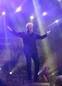 Holland standing onstage with arms outstretched