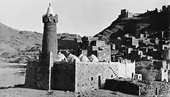 Partial view of Dhala in 1937, with the main mosque in the foreground. Atop the hill is the castle where the hereditary Amir of Dhala resided. Dhala, 65 miles north of Aden, lies 4,800 feet (1450 m) above sea level. It was then one of the states of the Aden Protectorate, strategically located near the border of the Protectorate and what was then the Imamate (Kingdom) of Yemen