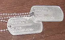 Two metal US Army dog tags with Atheist/FSM stamped on them