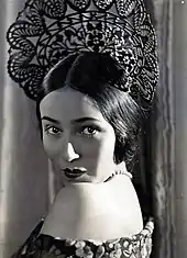 Del Río wearing what it seems to be a crown while being with her back turned and looking right in front of a camera