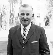 A black and white portrait of Dominic Olejniczak in a suit and tie