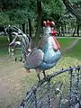 Cock sculpture of wrought "Tree of life" composition