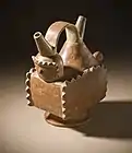 Double spout and strap handle vessel with a mythological figure; 400–1200; slip-painted ceramic; height: 19.37&nbsp;cm (7.mw-parser-output .frac{white-space:nowrap}.mw-parser-output .frac .num,.mw-parser-output .frac .den{font-size:80%;line-height:0;vertical-align:super}.mw-parser-output .frac .den{vertical-align:sub}.mw-parser-output .sr-only{border:0;clip:rect(0,0,0,0);clip-path:polygon(0px 0px,0px 0px,0px 0px);height:1px;margin:-1px;overflow:hidden;padding:0;position:absolute;width:1px}5⁄8 in.), width: 19.05&nbsp;cm (7.mw-parser-output .frac{white-space:nowrap}.mw-parser-output .frac .num,.mw-parser-output .frac .den{font-size:80%;line-height:0;vertical-align:super}.mw-parser-output .frac .den{vertical-align:sub}.mw-parser-output .sr-only{border:0;clip:rect(0,0,0,0);clip-path:polygon(0px 0px,0px 0px,0px 0px);height:1px;margin:-1px;overflow:hidden;padding:0;position:absolute;width:1px}1⁄2 in.), depth: 10.32&nbsp;cm (4.mw-parser-output .frac{white-space:nowrap}.mw-parser-output .frac .num,.mw-parser-output .frac .den{font-size:80%;line-height:0;vertical-align:super}.mw-parser-output .frac .den{vertical-align:sub}.mw-parser-output .sr-only{border:0;clip:rect(0,0,0,0);clip-path:polygon(0px 0px,0px 0px,0px 0px);height:1px;margin:-1px;overflow:hidden;padding:0;position:absolute;width:1px}1⁄16in.); Yotoco stage; Los Angeles County Museum of Art