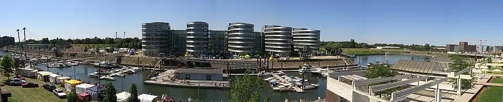 View of the Marina (left hand) and the “Five Boats” office complex, designed by the British architect Nicholas Grimshaw. On the right hand you can see the Holzhafen, which will be encircled by a projected hotel complex called Eurogate. The free space shown in the photograph to the left of Grimshaw’s 'boat building' does not actually exist any more (used for the “Hitachi Power Office”).