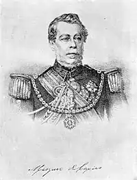 Lithograph depicting head and shoulders of a man with gray moustache wearing a military tunic with epaulettes and elaborate lanyards, several medals at his neck and breast, sash of office, and a prominent star on a heavy gold chain suspended from his shoulders