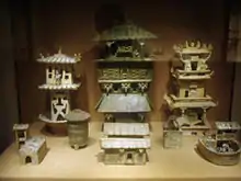 Among a large set of architectural models, three Eastern Han Dynasty watchtowers stand in the rear of this display